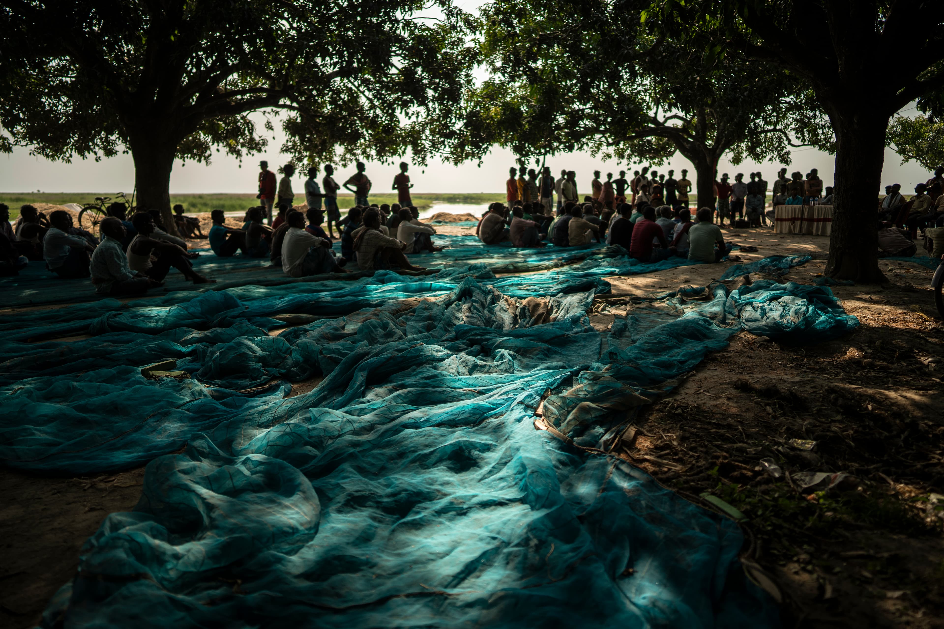 Community gathering beside blue fishing nets