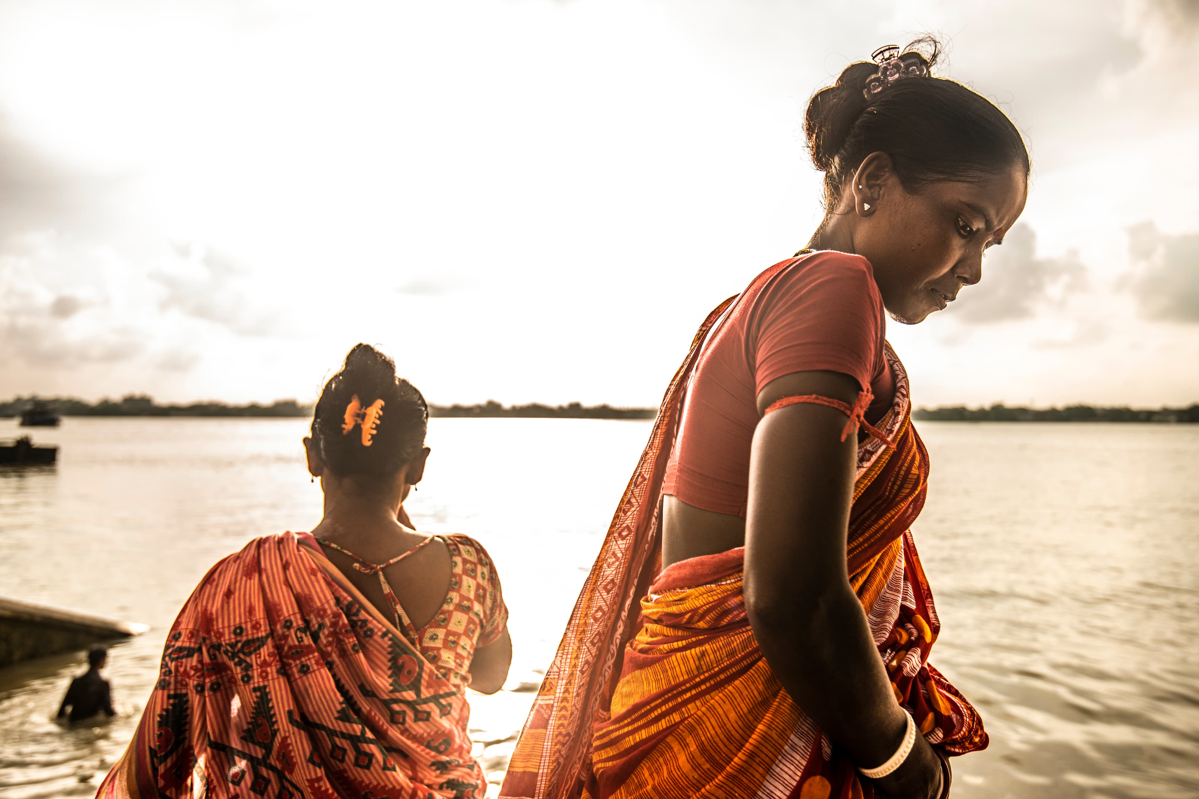 Women in red saris beside the river