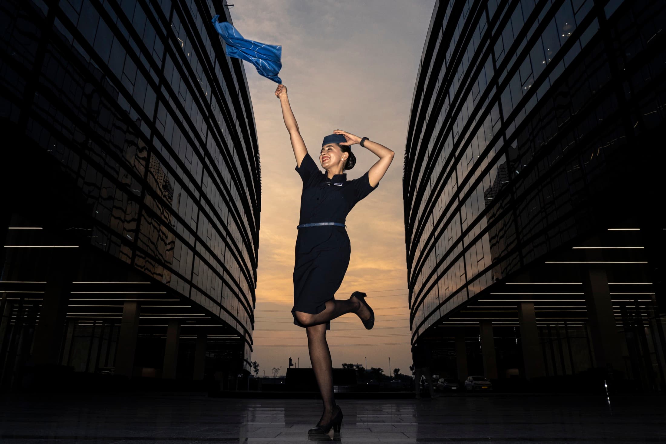 A uniformed woman holding a blue fabric between glass buildings