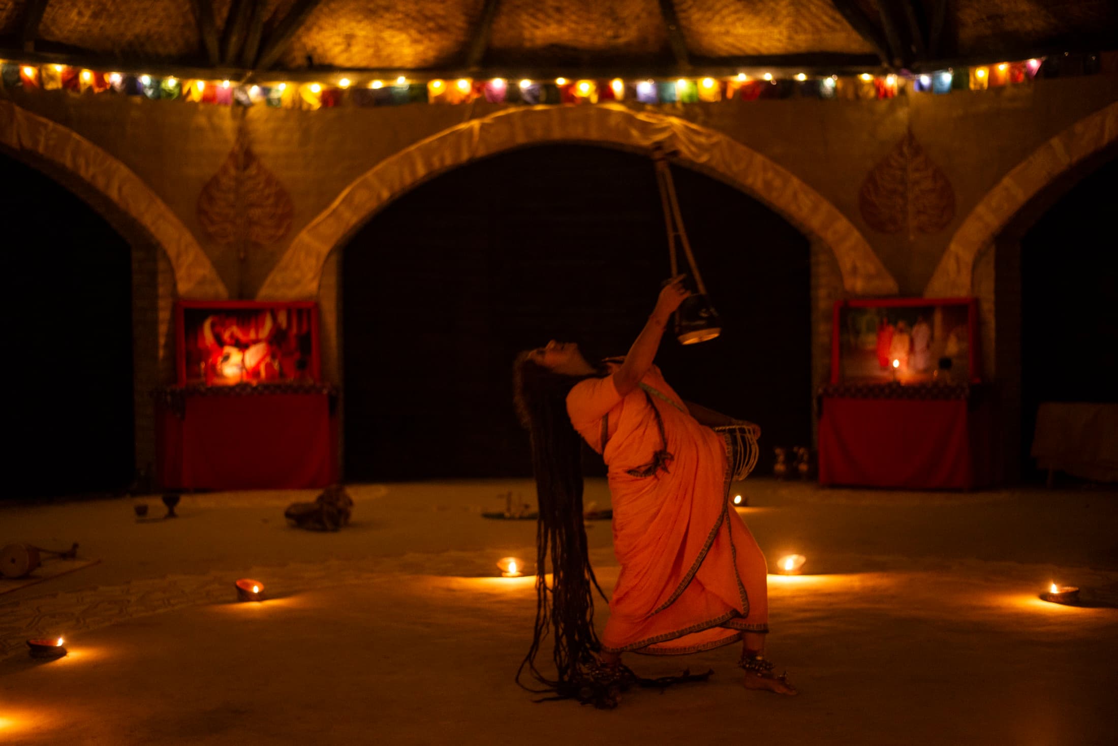 A performer in orange surrounded by warm lamps